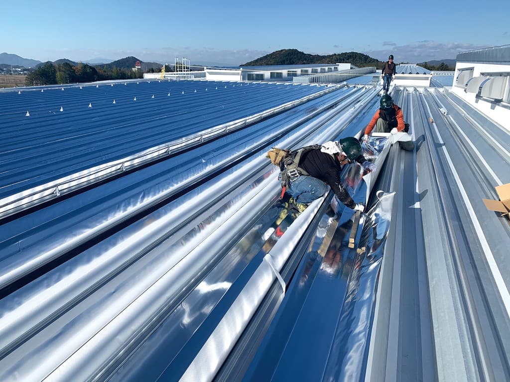 折板屋根に遮熱材を施工する作業員の様子